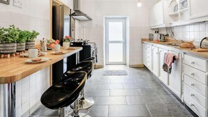 A modern kitchen with a wooden countertop, black bar stools, a stainless steel range hood, and a tiled backsplash. - 4 Bed in Cardigan (oc-82766) (Rhos-hill)