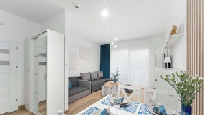 A modern living room with a dining area, a sofa, a coffee table, and a dining table set for two. - Cozy Studio with a Balcony | Parking (Grzybowo)
