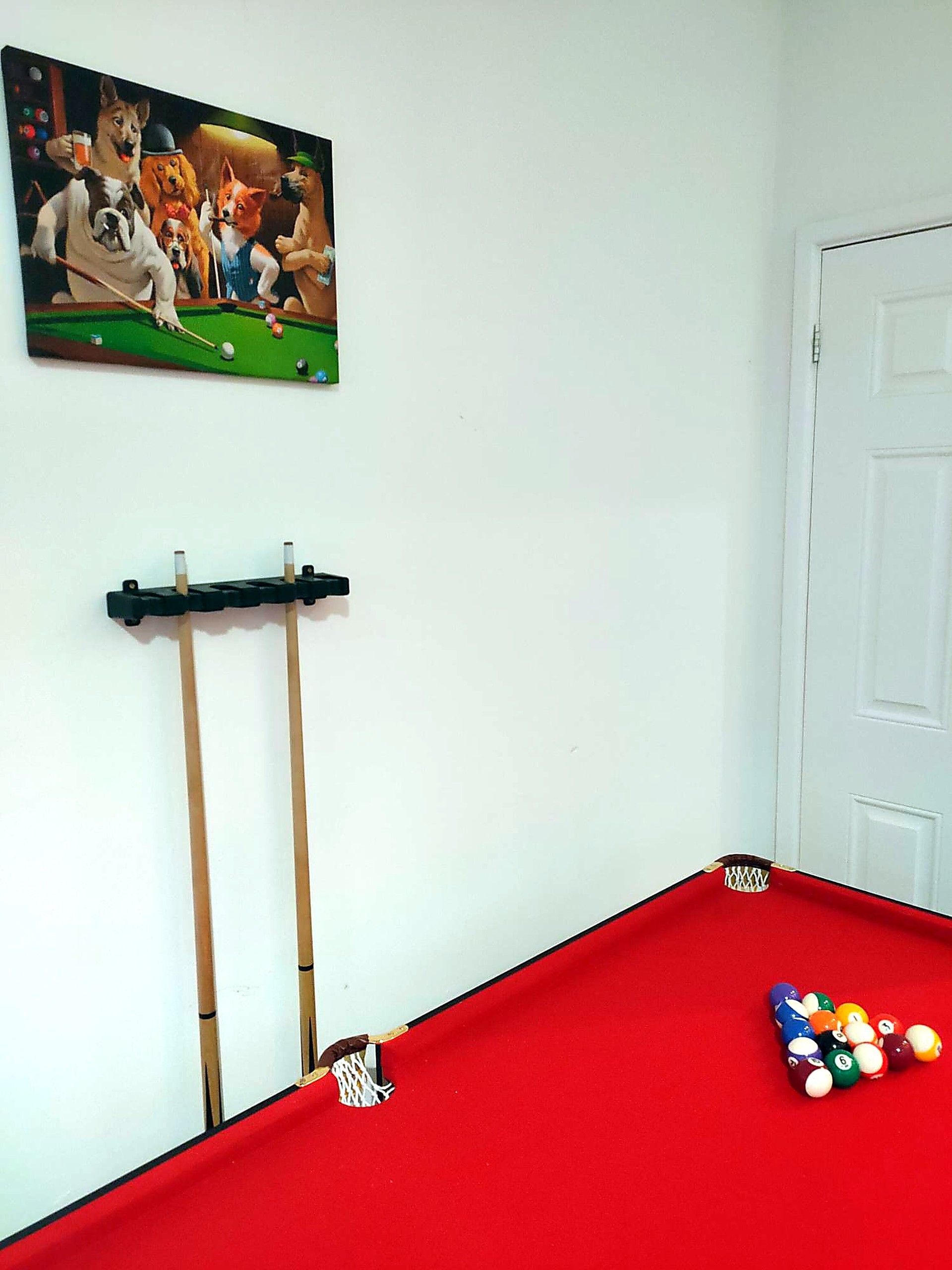 A billiards table with balls and cues, a door, and a wall-mounted picture.