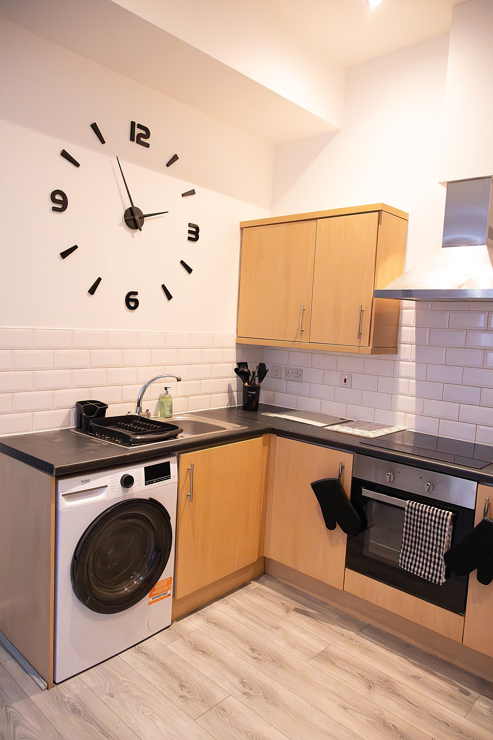 A compact kitchen with a built-in washing machine, a stove, and wooden cabinets.