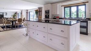 Une cuisine moderne avec des meubles blancs, un grand îlot central et un coin repas comprenant une table et des chaises.