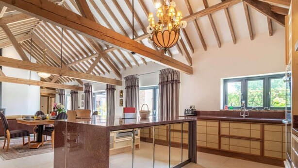 A spacious kitchen with a central island, wooden beams, and a large window. - 3 Bed in Lowestoft (oc-82802) (Lound)