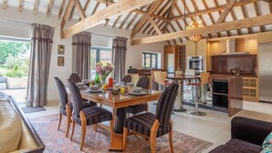 A dining area with a wooden table and chairs, a kitchen with modern appliances, and a view of the outdoors. - 3 Bed in Lowestoft (oc-82802) (Lound)