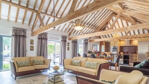 A spacious living area with a high wooden ceiling, two sofas, a coffee table, and a dining area in the background. - 3 Bed in Lowestoft (oc-82802) (Lound)