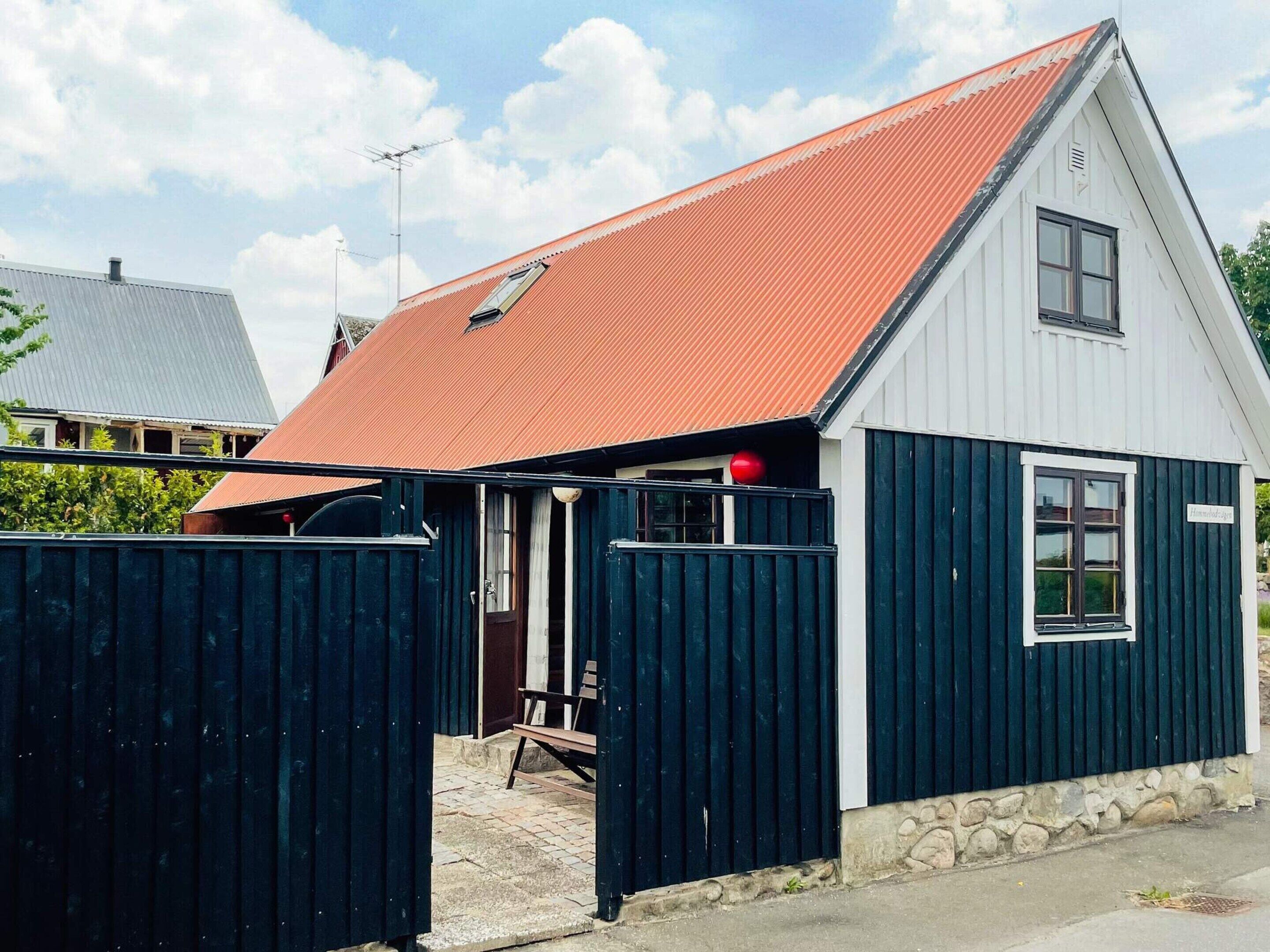 Pieni, yhden kerroksen rakennus, jossa on punainen katto, puuovi ja ikkuna.