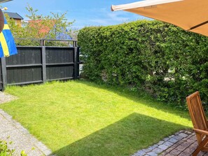 A well-maintained backyard with a wooden fence, a hedge, and a patio area with a chair. - 5 Person Holiday Home in Kivik (Kivik)