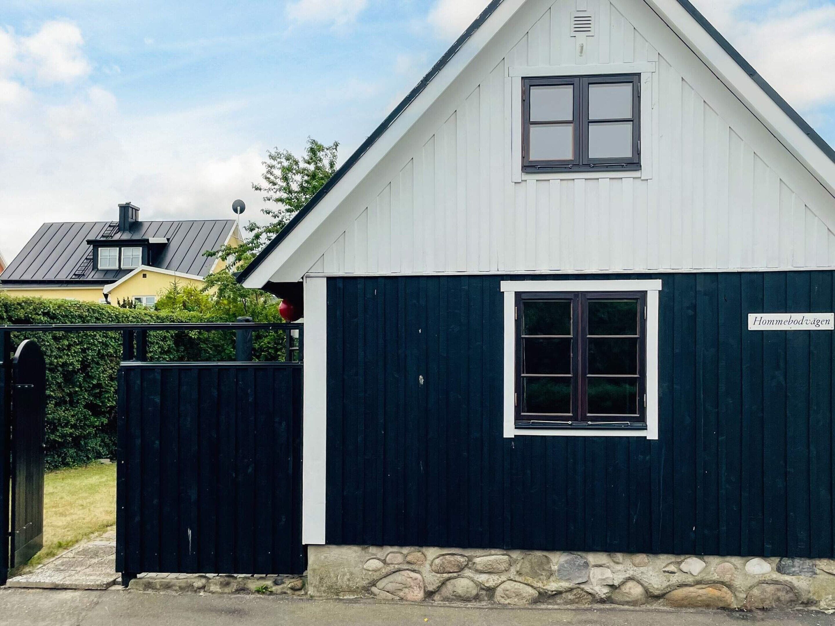 A single-story building with a dark blue exterior, a white trim around the windows, and a stone foundation.