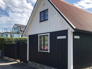 A small, single-story building with a dark exterior and a white trim. There are two signs on the building, one reading 'Hommebodvågen' and the other 'Mellbygrand.' - 5 Person Holiday Home in Kivik (Kivik)