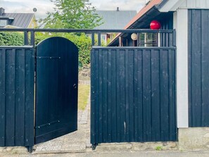 A black metal gate leading to a building with a red spherical object on the roof. - 5 Person Holiday Home in Kivik (Kivik)