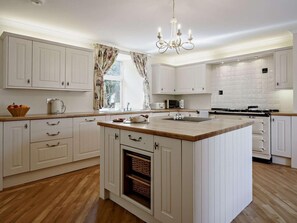 A modern kitchen with white cabinetry, a central island, a built-in oven, and a chandelier. - 3 Bed in Biggar (oc-82924) (Biggar)