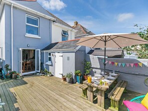 Une propriété résidentielle dotée d’une terrasse en bois, d’un espace barbecue et d’un petit jardin.