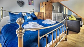 A bedroom with a curved bed, wooden ceiling beams, a wardrobe, and a staircase. - 4 Bed in Newquay (oc-82951) (Newquay)