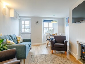 A living room with a sofa, armchair, dining table, and fireplace. - 2 Bed in Polruan (oc-82949) (Fowey)