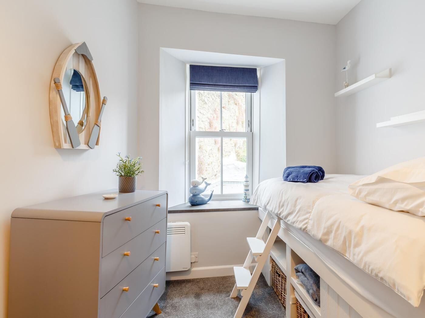 Un dormitorio con cama, cómoda, ventana y un pequeño escalón.