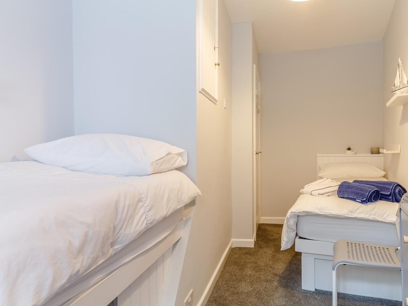 Une petite pièce propre, avec un lit simple, une chaise et une petite table.