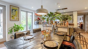 Una cocina moderna con una mesa larga de comedor, sillas e iluminación colgante.