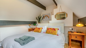 Un dormitorio con cama, mesitas de noche, una lámpara, un espejo y una decoración en la pared.