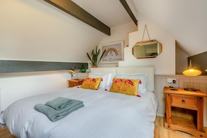 Ein Schlafzimmer mit einem Bett, Nachttischen, einer Lampe, einem Spiegel und einer Wanddekoration.