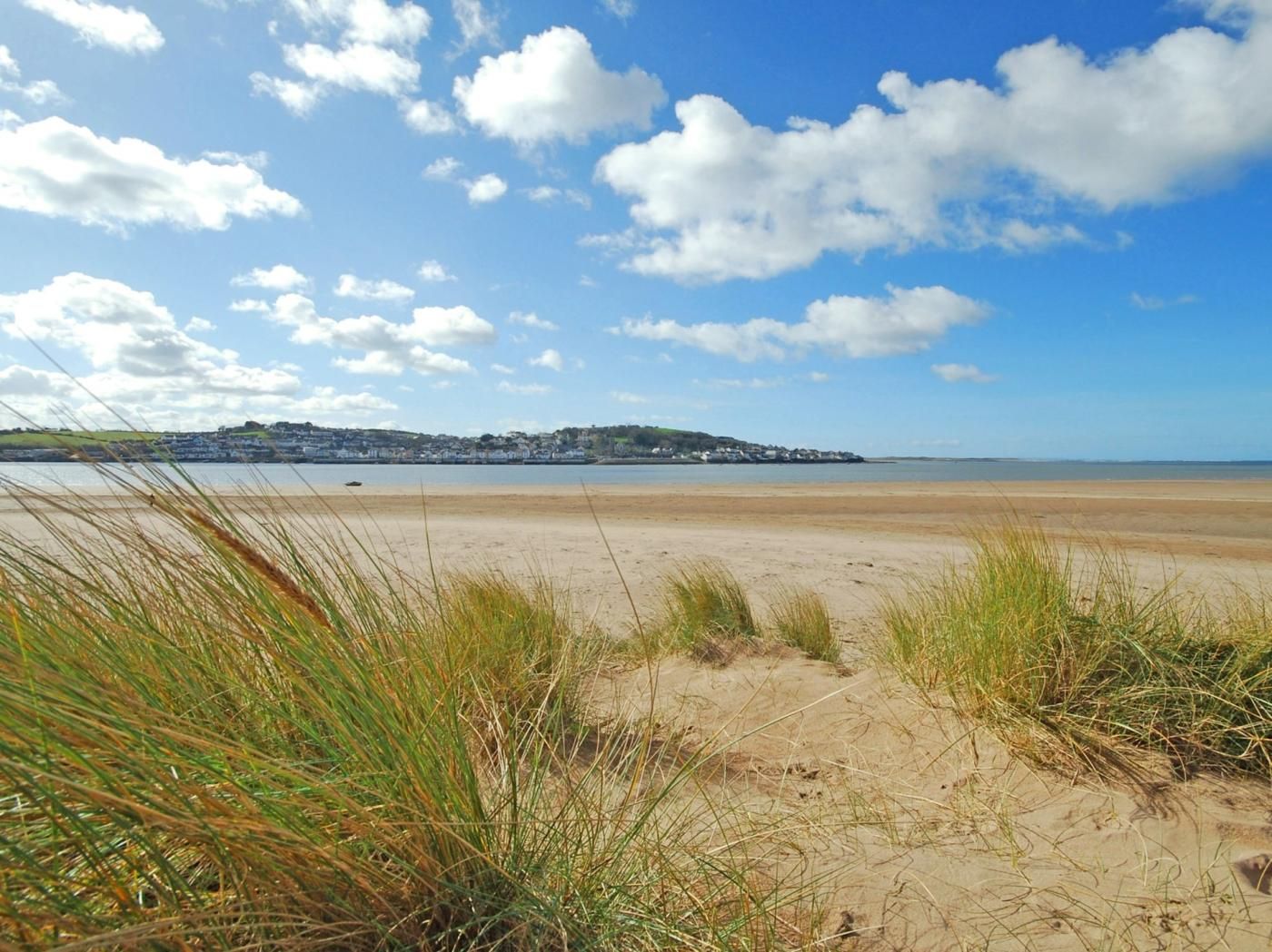Ein Strand mit Dünen und einer entfernten Stadt.