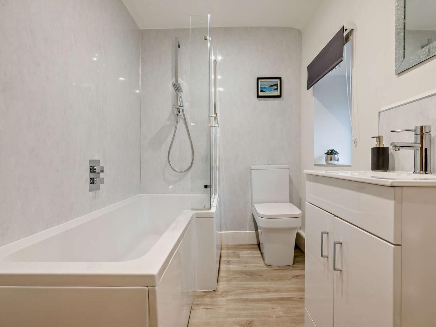 Un baño moderno con bañera, ducha, inodoro y tocador con espejo.