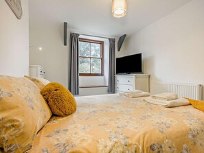 Ein Schlafzimmer mit Bett, Fernseher, Fenster und Heizkörper.