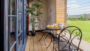 Ein Balkon mit Tisch, Stühlen, einer Topfpflanze und Frühstücksgebäck.