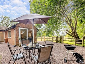 A patio with a table, chairs, an umbrella, and a barbecue grill. - 2 Bed in Crewe (oc-83192) (Audlem)