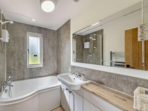 A modern bathroom with a bathtub, sink, and large mirror. - 2 Bed in Crewe (oc-83192) (Audlem)