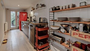 A modern kitchen with stainless steel appliances, wooden shelves, and a red refrigerator. - 2 Bed in Whitstable (oc-83291) (Whitstable)