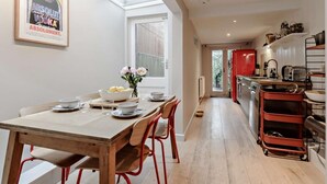 A modern kitchen with a red refrigerator, a dining area with a wooden table and chairs, and a skylight above the dining table. - 2 Bed in Whitstable (oc-83291) (Whitstable)