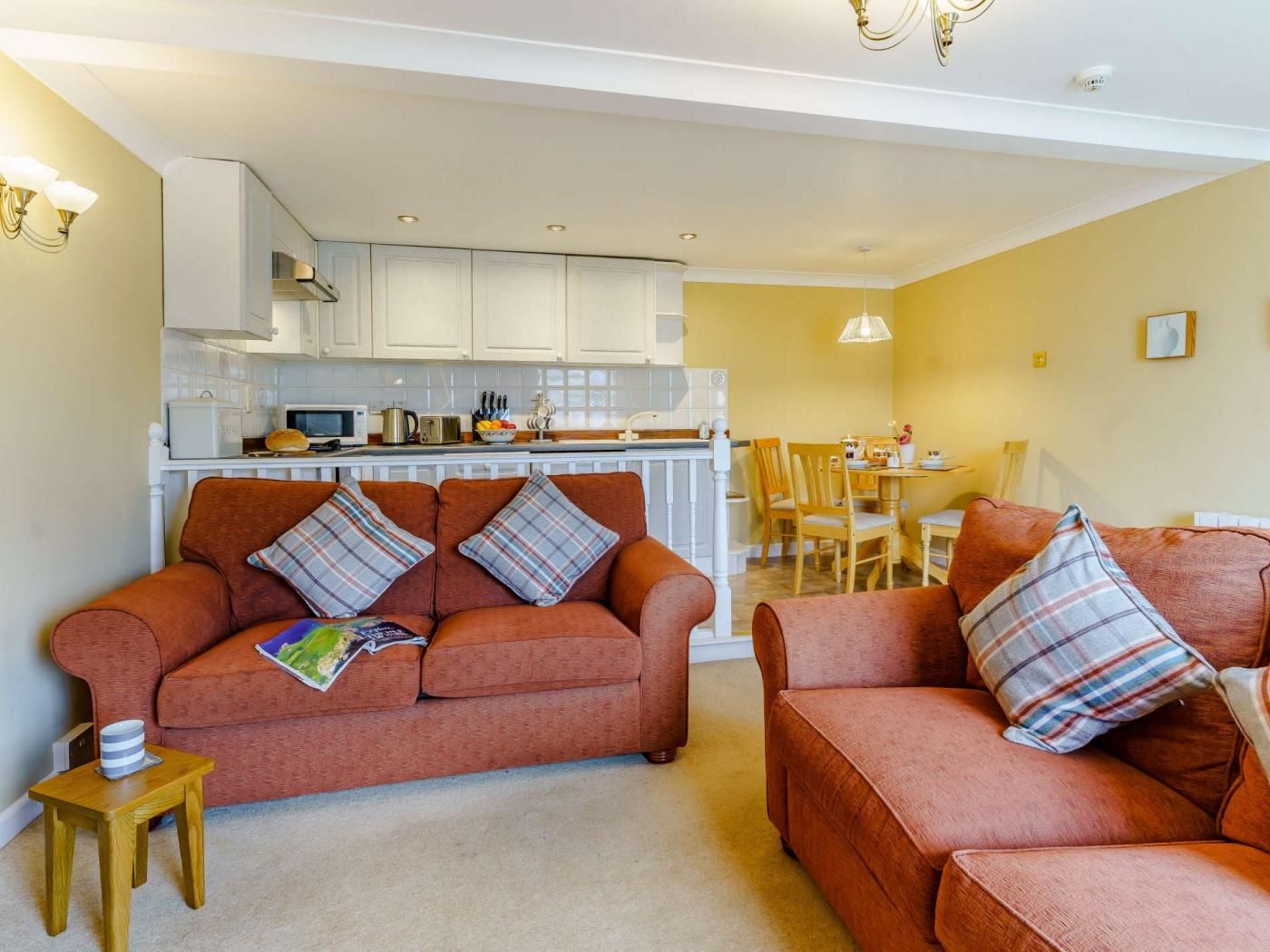 A living room with two sofas, a small table, and a kitchen in the background.