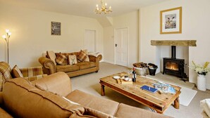 A cozy living room with a sofa, coffee table, fireplace, and a chandelier. - 3 Bed in Great Ayton (oc-83328) (Great Ayton)
