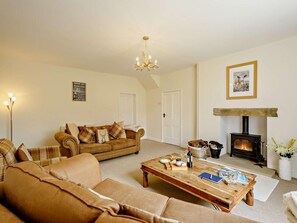 A cozy living room with a sofa, coffee table, fireplace, and a chandelier. - 3 Bed in Great Ayton (oc-83328) (Great Ayton)