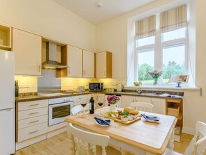 A modern kitchen with white cabinetry, a built-in oven, a microwave, and a dining area with a table set for two. - 1 Bed in Langholm (oc-83343) (Langholm)
