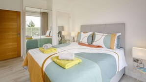 Ein Hotelzimmer mit Bett, Nachttisch, Lampe und Blick ins Freie.