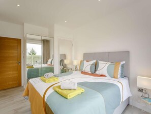 Ein Hotelzimmer mit Bett, Nachttisch, Lampe und Blick ins Freie.
