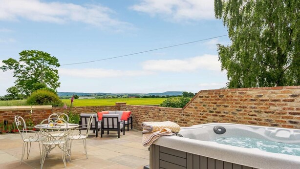 Eine Terrasse mit Whirlpool, Sitzgelegenheit und Blick auf die Landschaft.