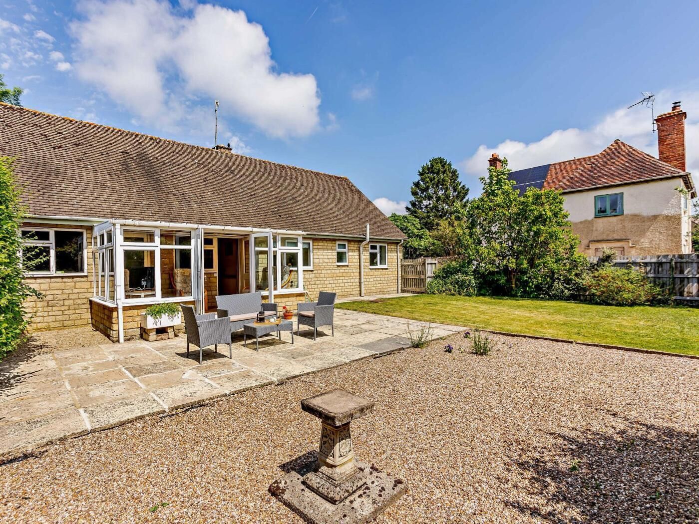 A house with a patio, a stone bench, and a garden.