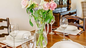 A dining table set with plates, glasses, and a vase of flowers. - 2 Bed in Moreton In Marsh (oc-83379) (Blockley)