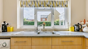 A kitchen with a window, a sink, a coffee maker, and a kettle. - 2 Bed in Moreton In Marsh (oc-83379) (Blockley)