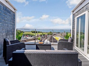 Un balcone con mobili in vimini, un barbecue e vista su un parcheggio e aree verdi.