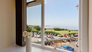 A room with a large window overlooking a parking area and a view of the sea. - 2 Bed in Woolacombe (oc-83425) (Woolacombe)