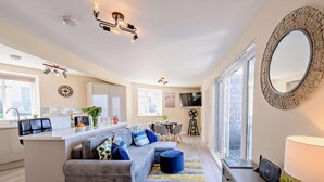 A modern living room with a sofa, a dining area, a kitchen, and a large mirror. - 2 Bed in Woolacombe (oc-83425) (Woolacombe)