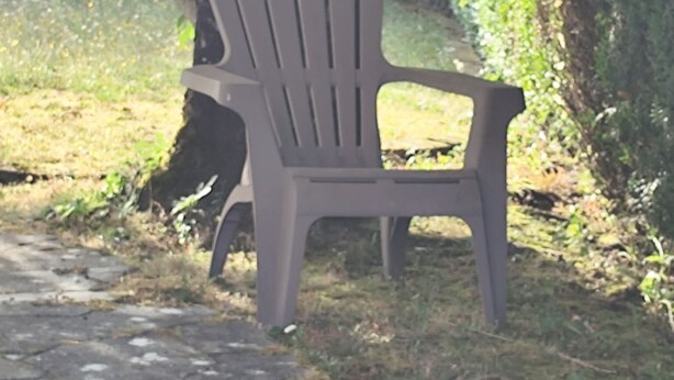 Muovinen tuoli ulkona, vehreyden ja kivipolun ympäröimänä.