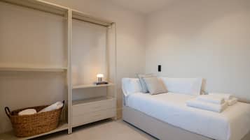 A bedroom with a bed, a bedside table, a lamp, a wardrobe, and a wicker basket.