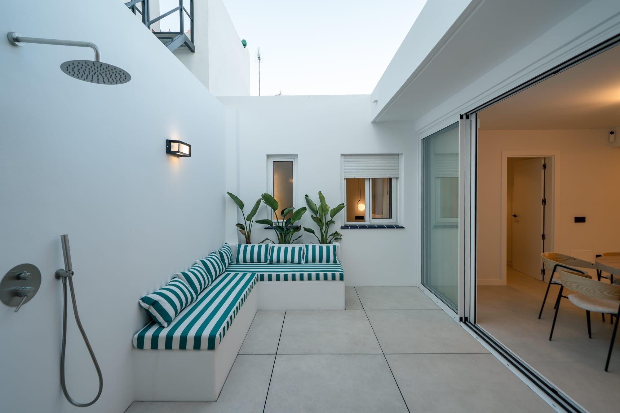 A modern outdoor living area with a built-in bench, a shower, and a dining table.