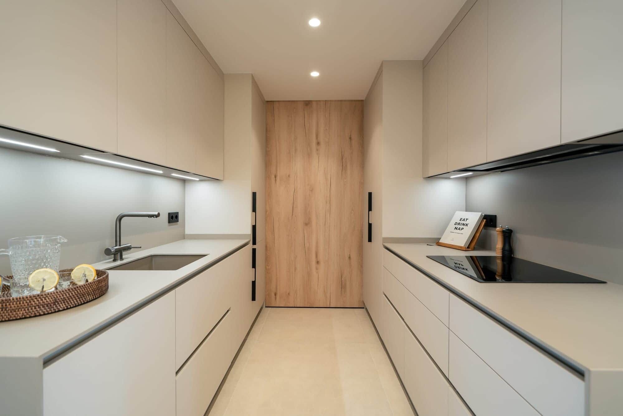 Ett modernt kök med en central avdelare i trä, rostfria vitvaror och en minimalistisk design.