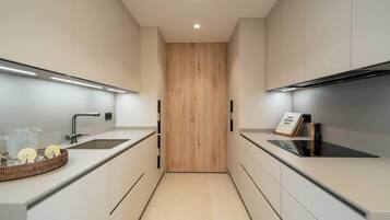 Ett modernt kök med en central avdelare i trä, rostfria vitvaror och en minimalistisk design.