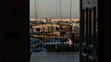 A view through an open door of a marina with boats docked and a stone pathway leading to the water.