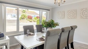 En matplats med ett bord för fyra personer, en kristallkrona och utsikt över en bostadsgata.